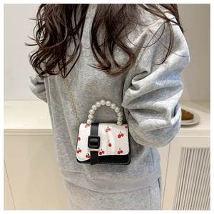 Detail of cute cherry print mini bag with contrast trim and pearl handle on model