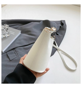 Détail d'un sac seau blanc en cuir grainé avec finitions dorées et bandoulière fine