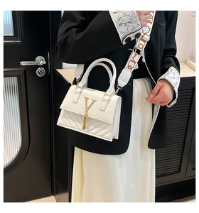 Detail of white leather shoulder bag with gold V logo, tassel and patterned woven strap