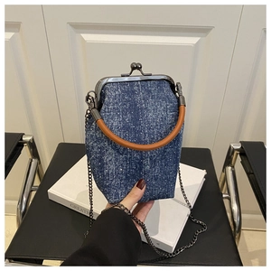 Détail du sac seau en denim bleu à pois blancs, avec poignée en cuir et bandoulière