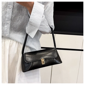 Detail of a black faux leather baguette bag with a golden metal buckle for women