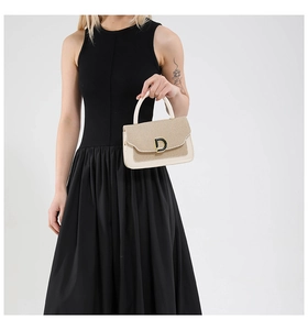 Dettaglio di elegante borsa tessuta bicolore con fibbia a D metallica in mano