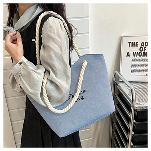 Detail view of light blue textured tote bag with thick white rope handles and Fashion print