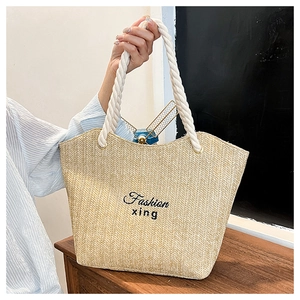 Detail of hand-woven straw tote with black embroidery and thick cotton rope handles