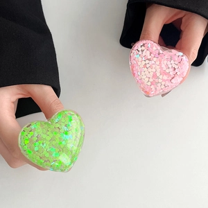Close-up of sparkling heart-shaped phone grips with green and pink sequins inside