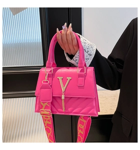 Detail of fuchsia leather handbag with gold V logo, tassel and wide patterned strap