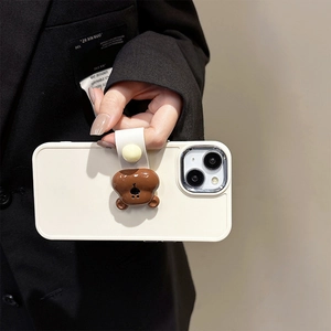 Close-up of beige iPhone case featuring a 3D brown bear ring holder with leather strap