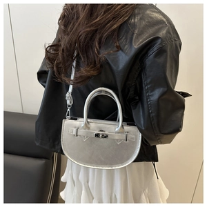 Détail du sac selle argenté en similicuir brillant avec boucle métallique et bandoulière