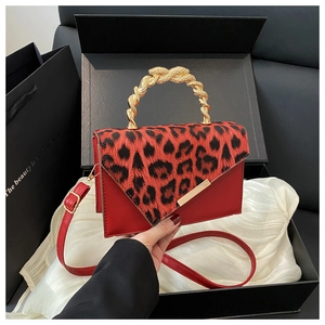 Detailed view of red leopard print handbag with gold snake-shaped handle on silk lining