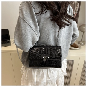 Detailed close-up of black crocodile pattern PU leather bag with silver metal chain