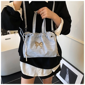 Close-up of light blue drawstring bag with a gold butterfly metal piece and shiny texture