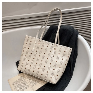 Detail of cream white leather tote bag featuring cartoon bear and rhombus patterns