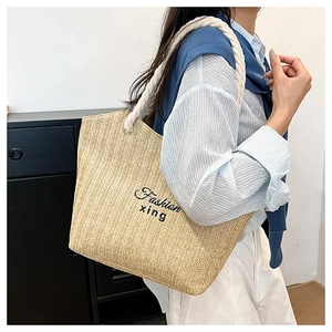Detail of hand-woven straw tote bag with braided rope handle and fashion embroidery