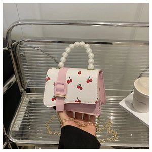 Detailed view of mini cherry print bag with pearl handle and golden chain strap