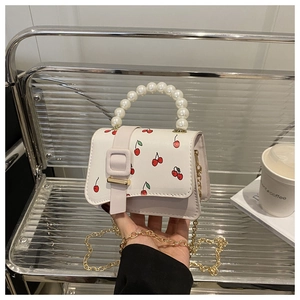 Detail of white mini crossbody bag with cherry print and faux pearl handle