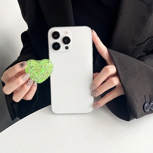 Detail of a green sequin heart phone grip holder on a smartphone held by a model