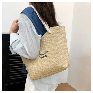 Detail of straw tote bag showing V-shaped weave texture and sturdy cotton rope handles