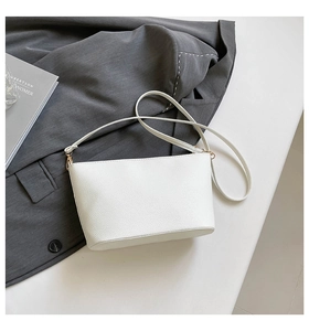 Gros plan du sac seau blanc en cuir grainé avec des boucles en métal doré élégantes