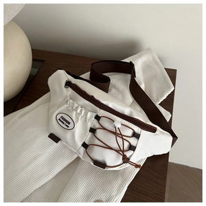 Detail of white nylon crossbody bag featuring brown elastic drawstring and fashion patch