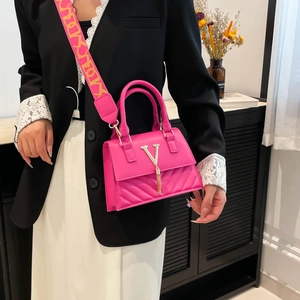Fuchsia crossbody bag with gold V-logo and colorful wide strap on stylish model