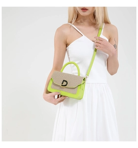 Dettaglio delle cuciture a contrasto, trama tessuta beige e ecopelle verde sulla borsa