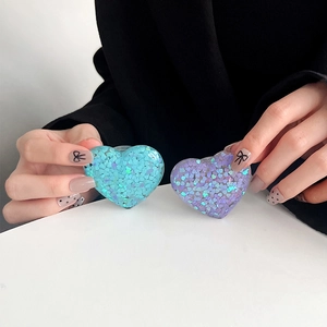 Close-up of heart-shaped sequin glitter phone grips in blue and purple colors