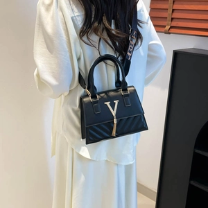 Fashionable black crossbody bag with gold V-logo, fringe, and a wide printed strap