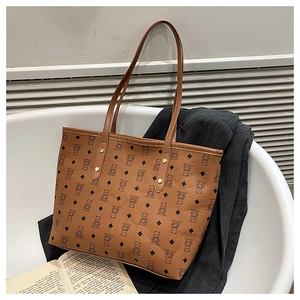 Detail of brown tote bag with bear pattern and gold rivet accents on a fabric surface
