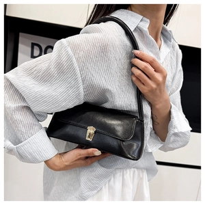 Detail view of the sleek black leather shoulder bag featuring a golden rectangular clasp