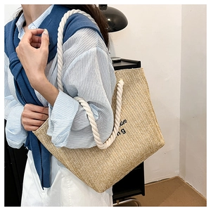 Detail of woven straw tote bag with cotton rope handles shown on shoulder with stripes