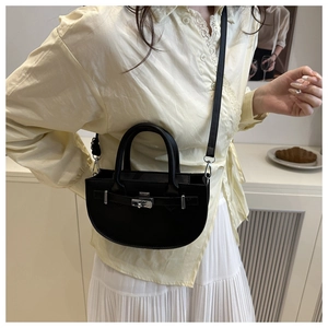 Détail d'un sac demi-lune en similicuir noir avec fermoir en métal argenté et bandoulière réglable