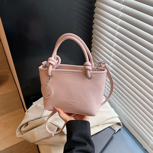 Fashionable light pink PU leather handbag with top handles and a round smiley charm