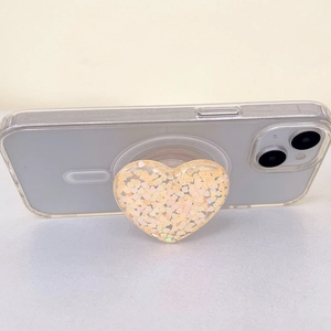 Macro detail of heart-shaped phone grip with glitter sequins on a transparent case