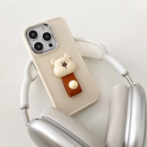 Detail of cream bear phone case with brown leather strap on a silver headphone stand