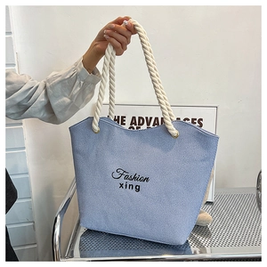Detail of light blue denim tote bag with white rope handles and Fashion xing embroidery