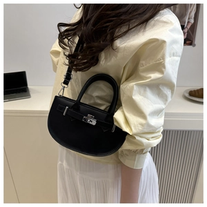 Détail d'un sac demi-lune en cuir noir avec fermoir rotatif argenté et poignée