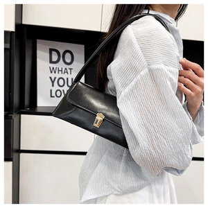 Detail of minimalist black patent leather shoulder bag with gold square metal buckle