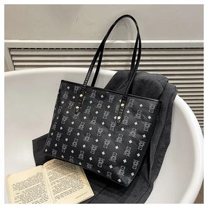 Detail of black bear print tote bag featuring pebbled texture and gold rivet hardware