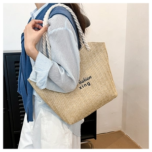 Detail of beige straw tote bag featuring woven V-texture and cotton rope handles