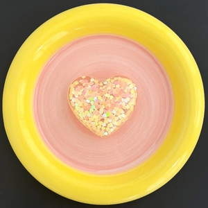 Macro view of heart-shaped glitter phone stand on a decorative ceramic dish