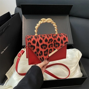 Fashionable leopard print handbag with a red leather body and unique golden snake handle