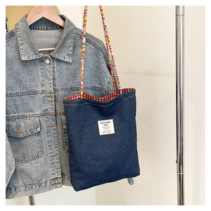 Détail du sac cabas en denim avec bandoulière en perles et doublure à carreaux rouges