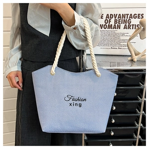 Close-up of light blue denim tote bag with white rope handles and Fashion xing embroidery
