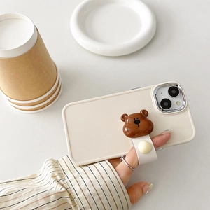 Close-up of cream silicone phone case with brown 3D bear stand and white leather wrist strap