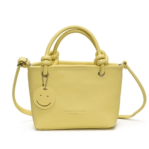 Fashionable pale yellow PU leather handbag with circular ring handles and smiley charm