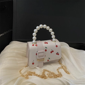 White mini crossbody bag with red cherry print and large pearl top handle