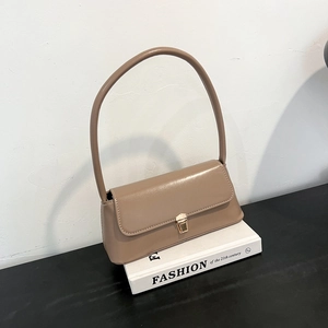 Chic khaki baguette bag with golden buckle on books in a minimalist setting