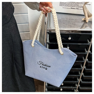 Detail of light blue denim tote with Fashion xing embroidery and rope handles
