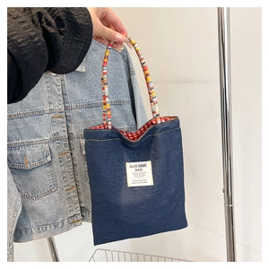 Détail du sac cabas en jean avec anse tressée arc-en-ciel et doublure à carreaux