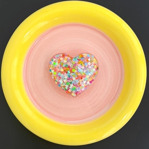 Detail shot of heart-shaped glitter phone socket with colorful sequins inside a resin shell